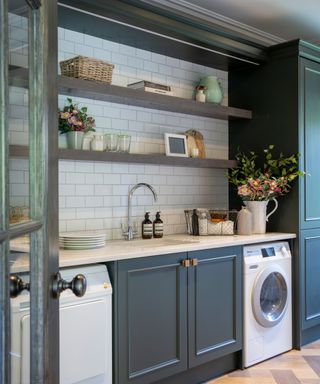 Modern laundry room with white subway tiles and dark contrast cabinets