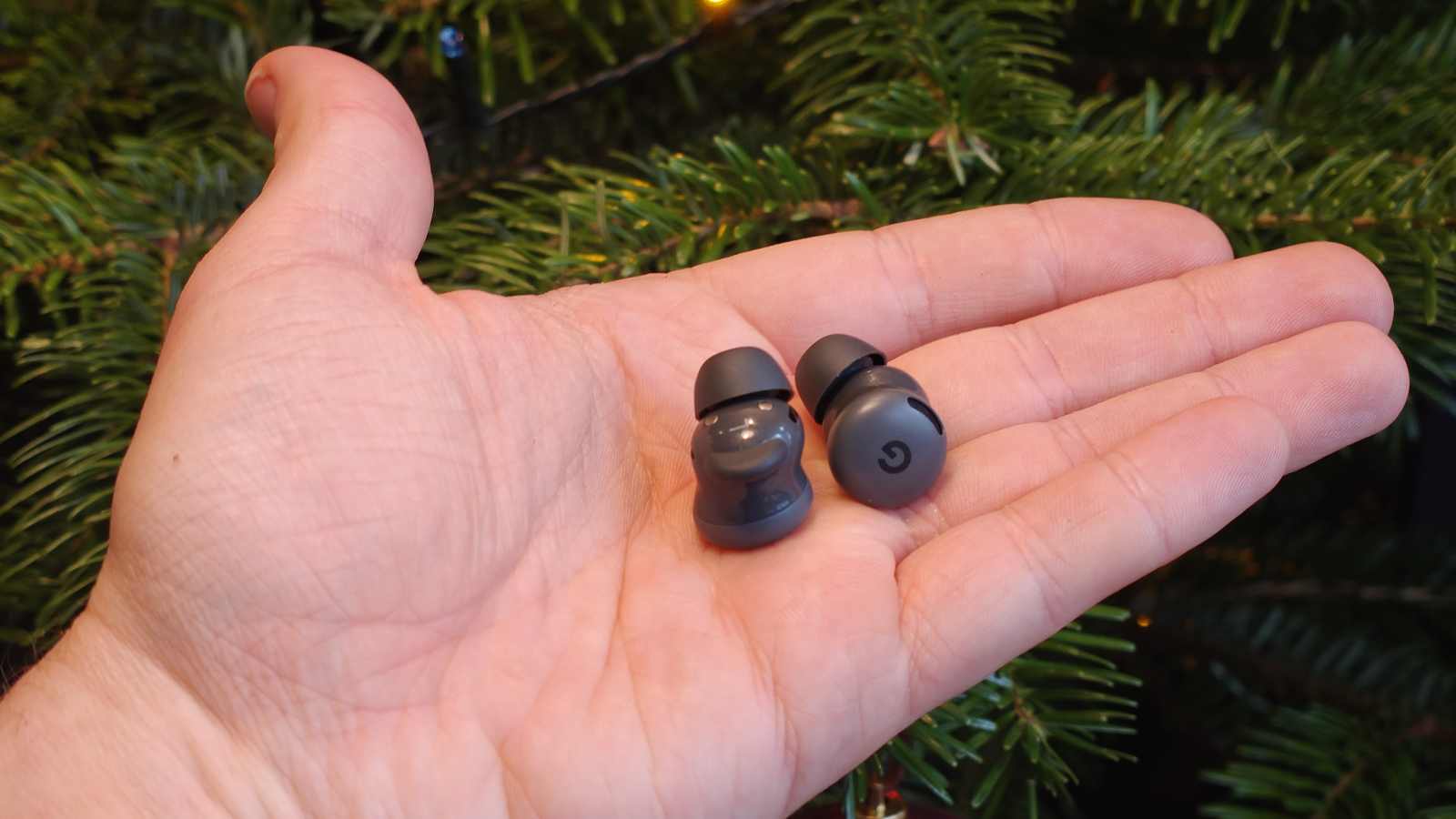 The Google Pixel Buds 2a buds in a man's hand.