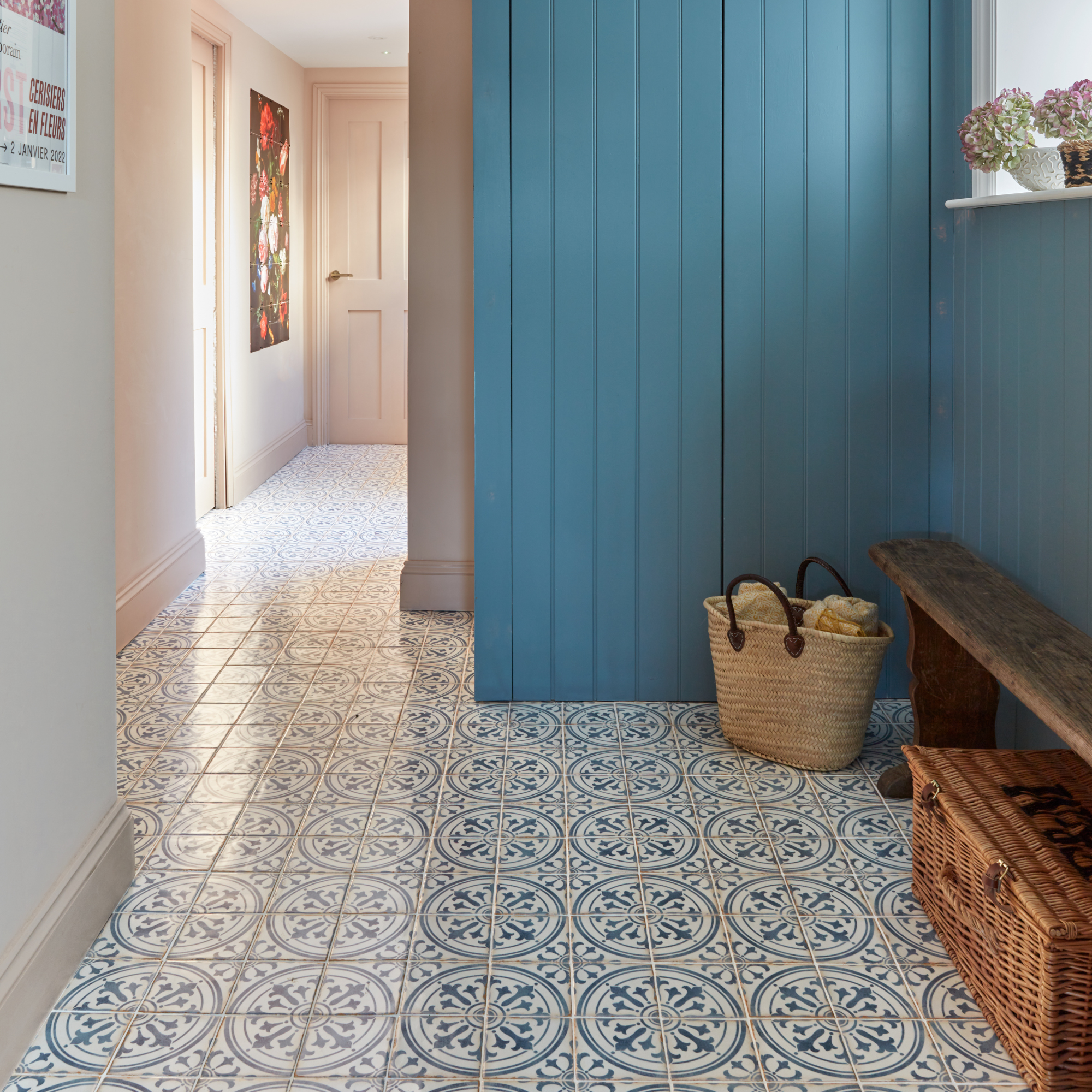boot room hallway area with blue painted storage cupboards, patterned floor tiles, and a bench