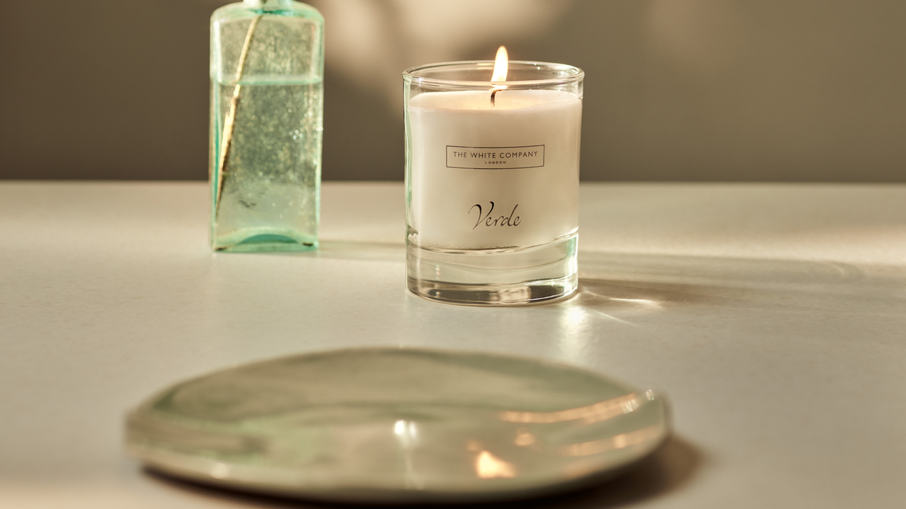 White Company Verde signature candle next to small green trinket dish.