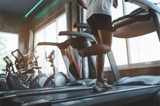 A man running on a treadmill at the gym.