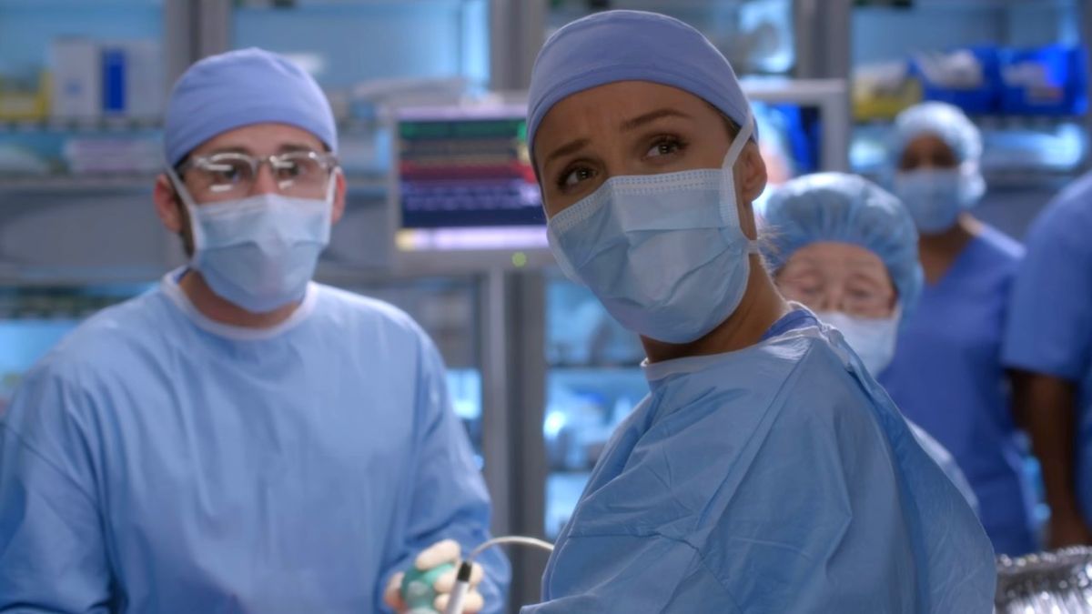 Camilla Luddington looks up while wearing scrubs in the operating room on Grey&#039;s Anatomy.