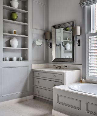 An example of bathroom storage ideas showing a gray bathroom with fitted storage shelves and a mirror on the wall