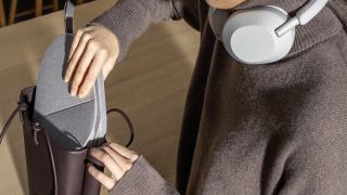 Sony WH-1000XM5 review: Woman placing the headphones' carry case into a handbag