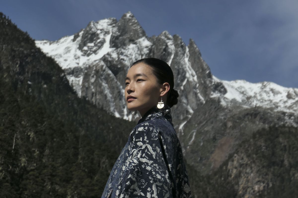 Portrait of a woman in a shawl in front of snowy mountains