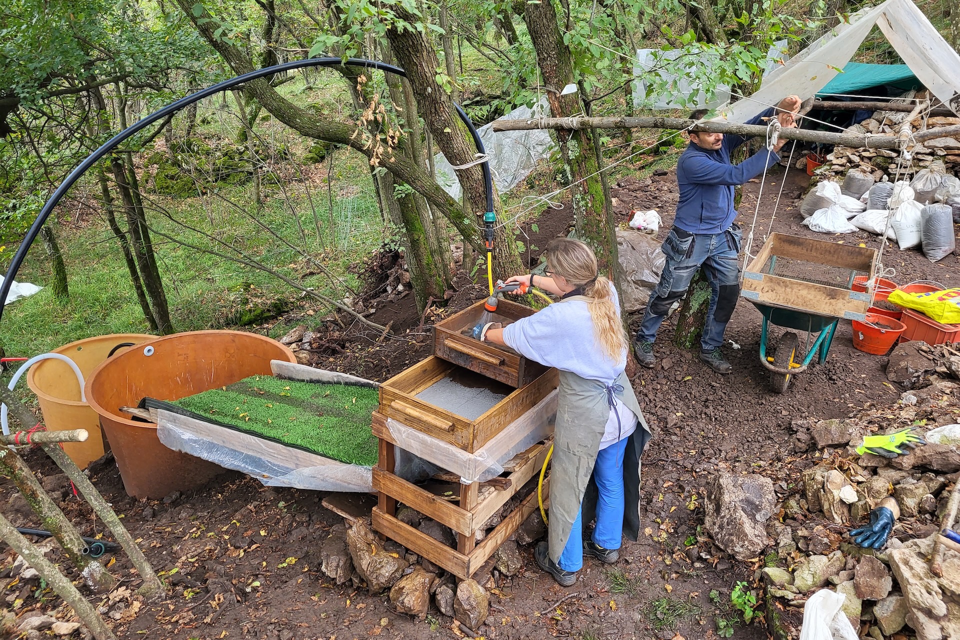 A photograph of people sieving soil in the woods