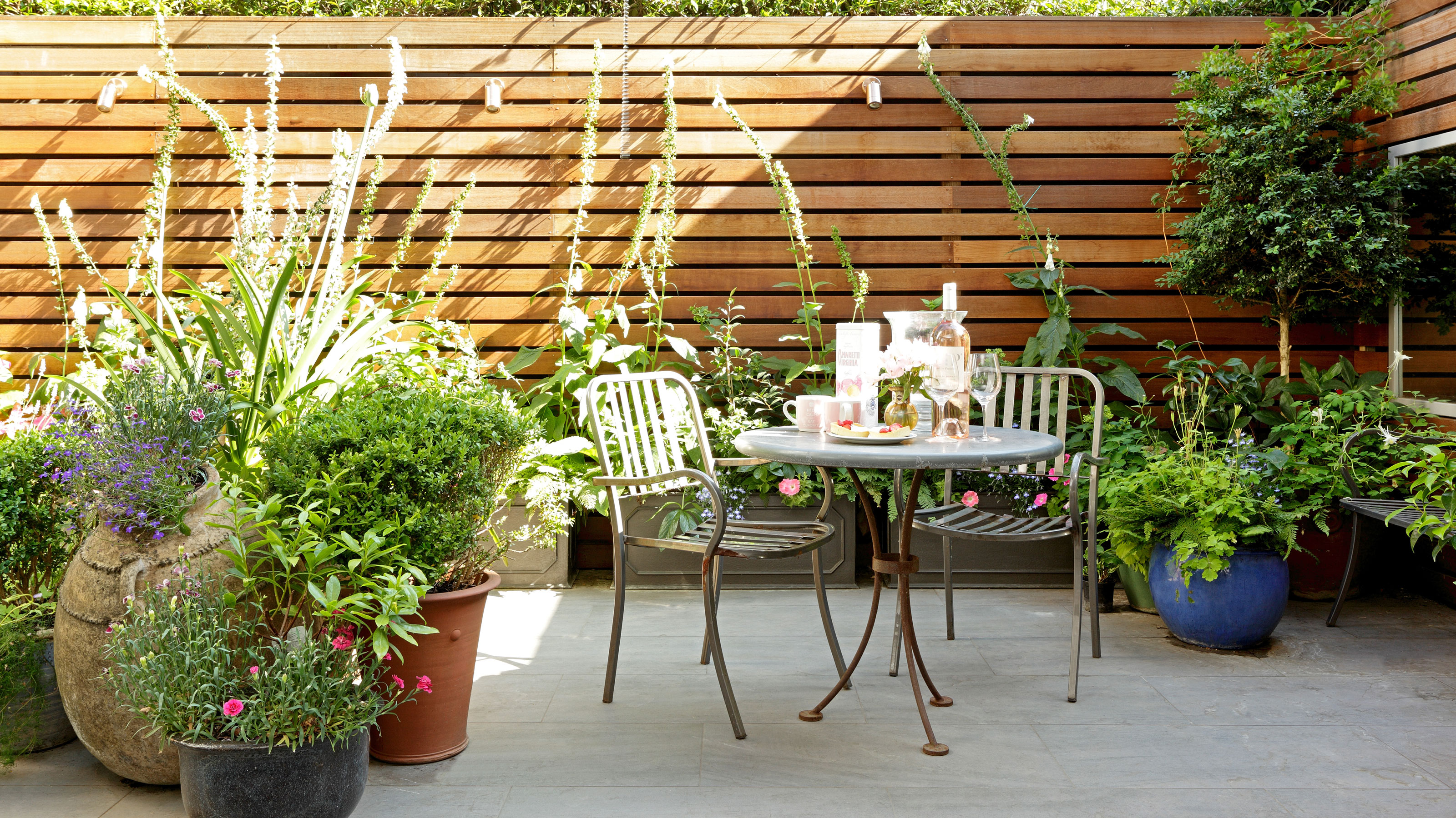 bistro set in patio area surrounded by plants and horizontal fencing panels