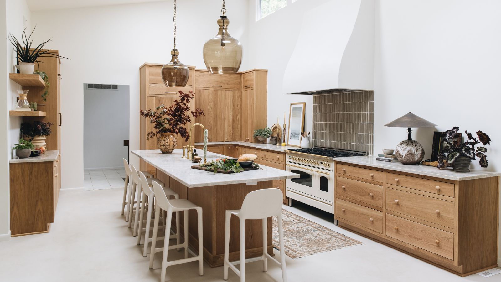 A large kitchen with white walls, marble countertops, and wooden cabinets