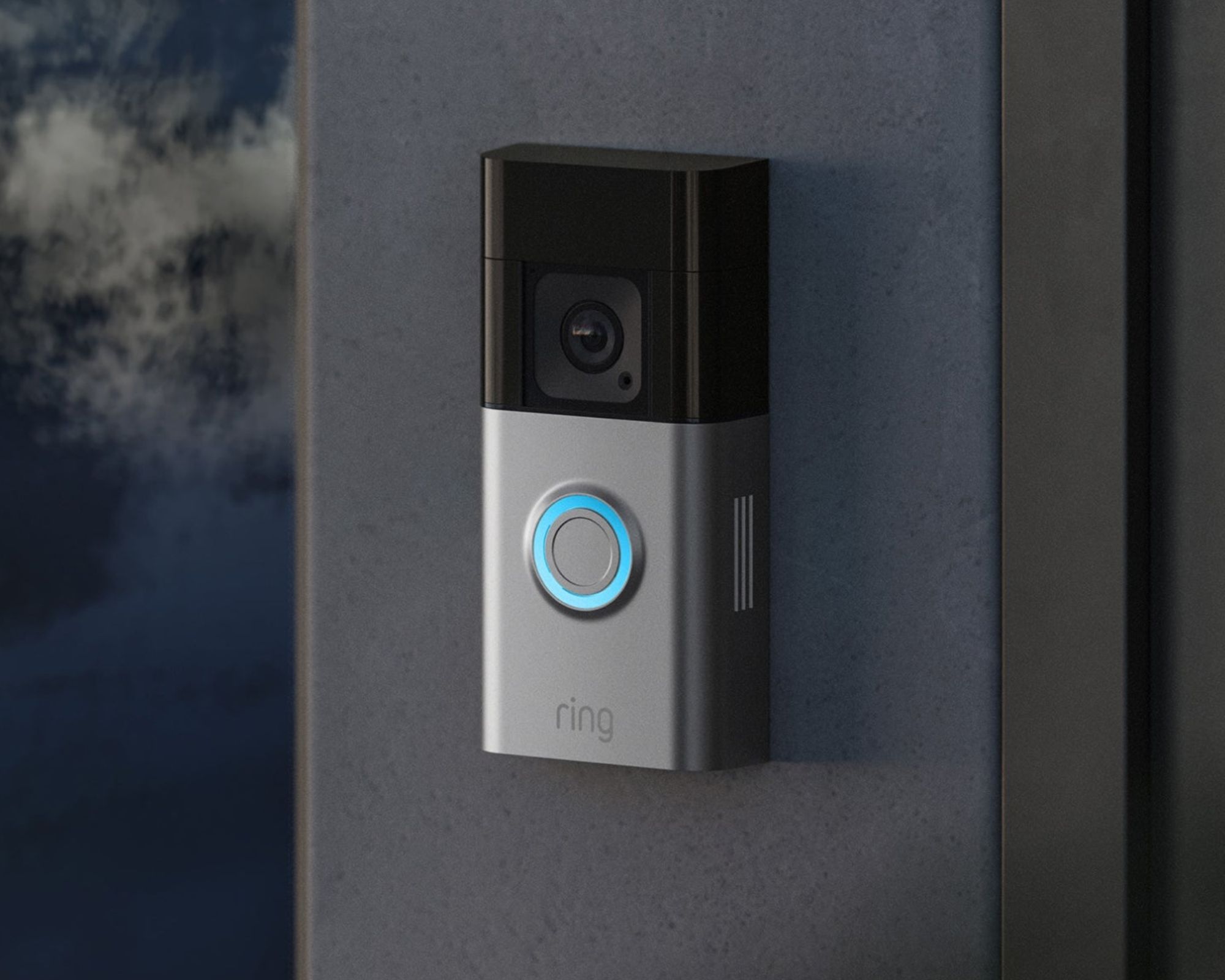 A close-up image of the silver and black Ring Battery Doorbell Pro installed on a dark grey wall.