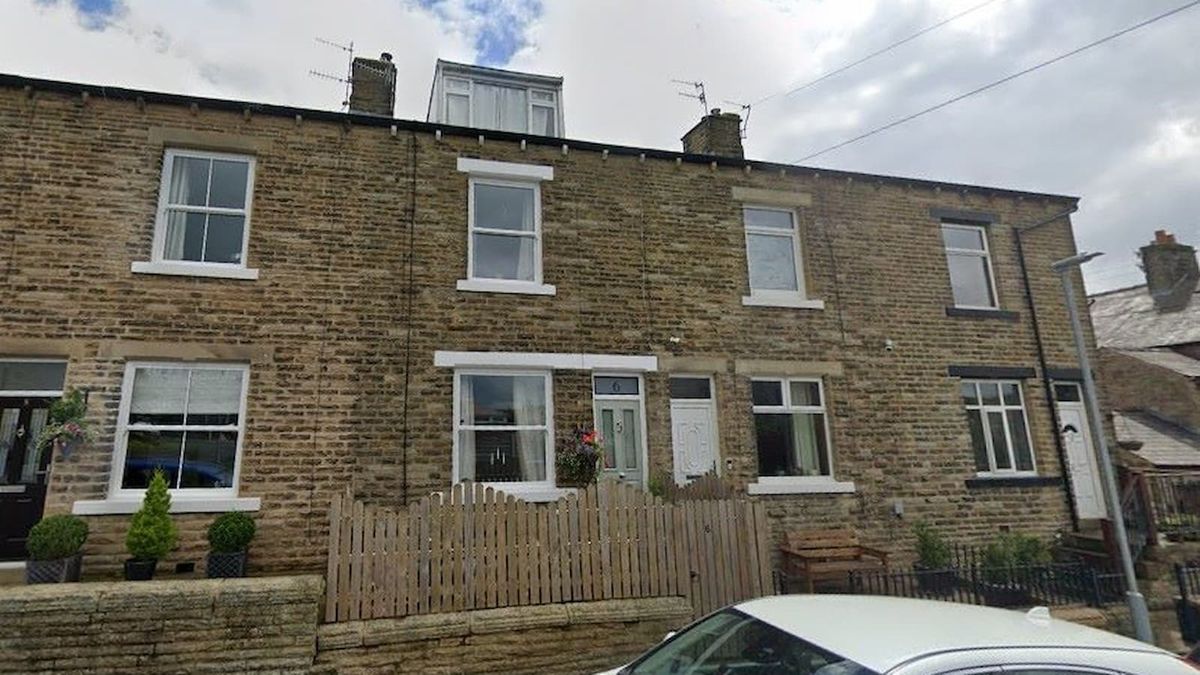 The front of a Victorian house with a stone wall and 6 foot wooden fence