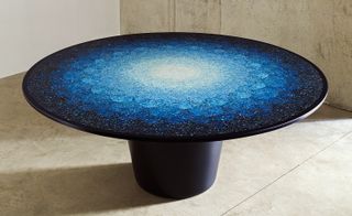 Low round table with white center fading through shade of blue to black on the edge