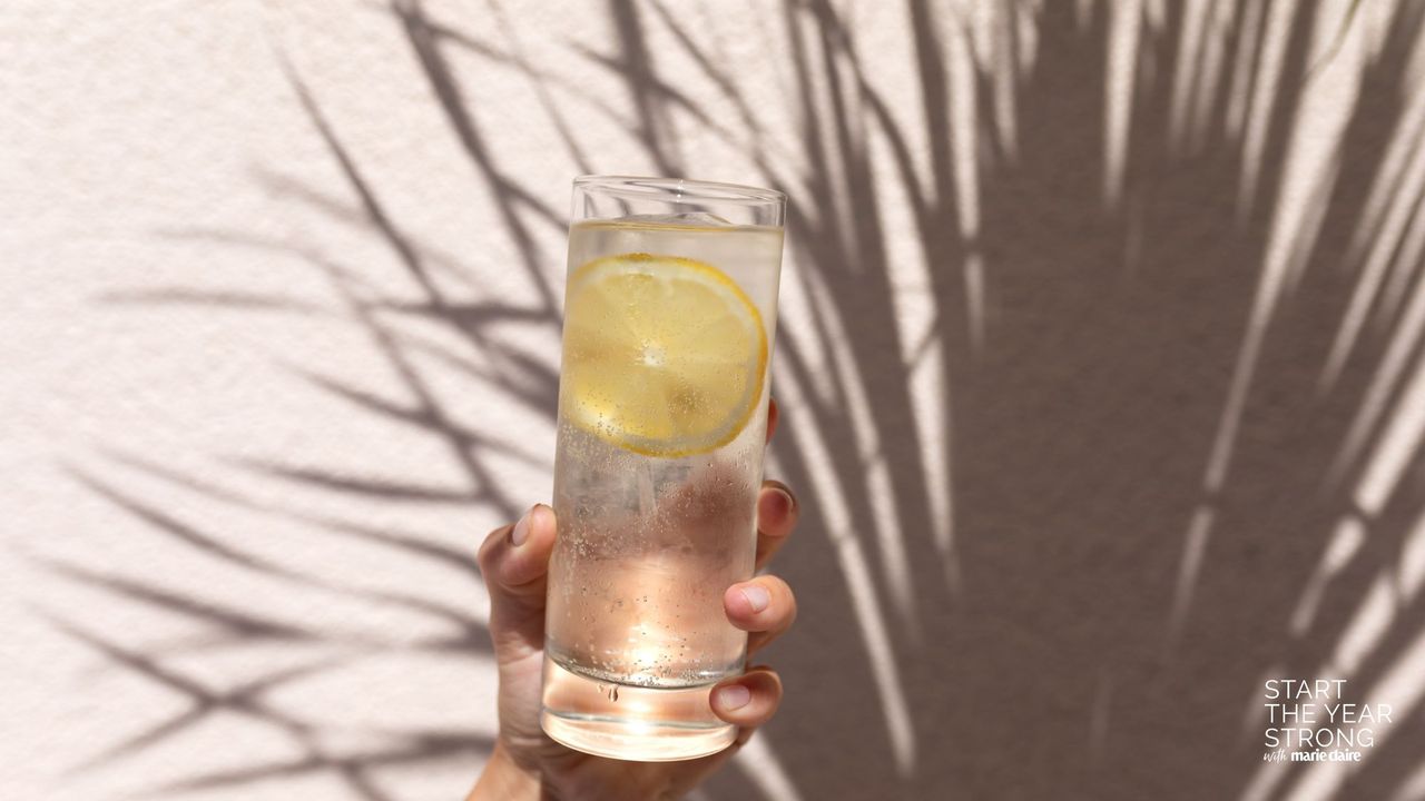 A woman holding a glass of lemon water