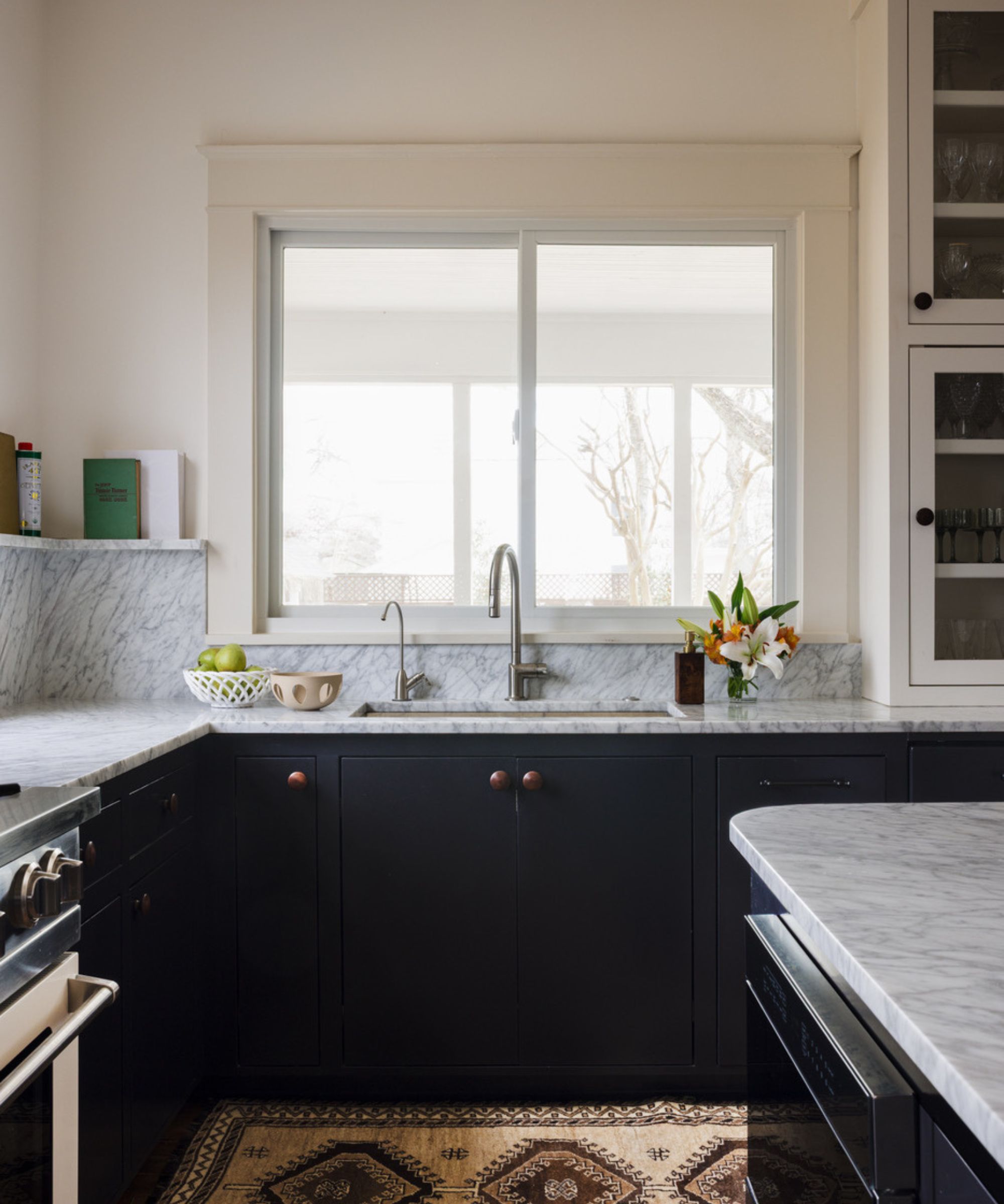 modern kitchen with warm white walls, marble countertops, dark blue cabinets