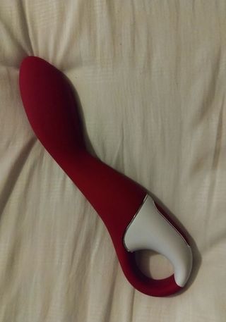 Satisfyer Heated Thrill review image by Ness Cooper The vibrator in red and white on bedding