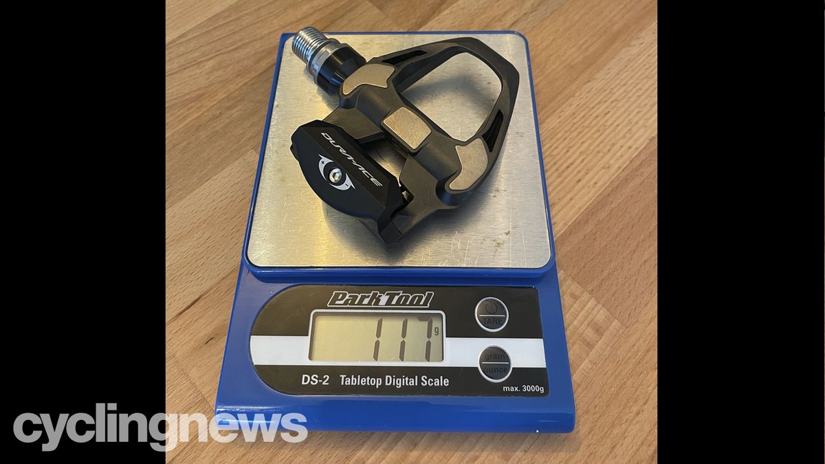 A Shimano Dura-Ace pedal on a Park Tools scale showing a weight of 117 grams