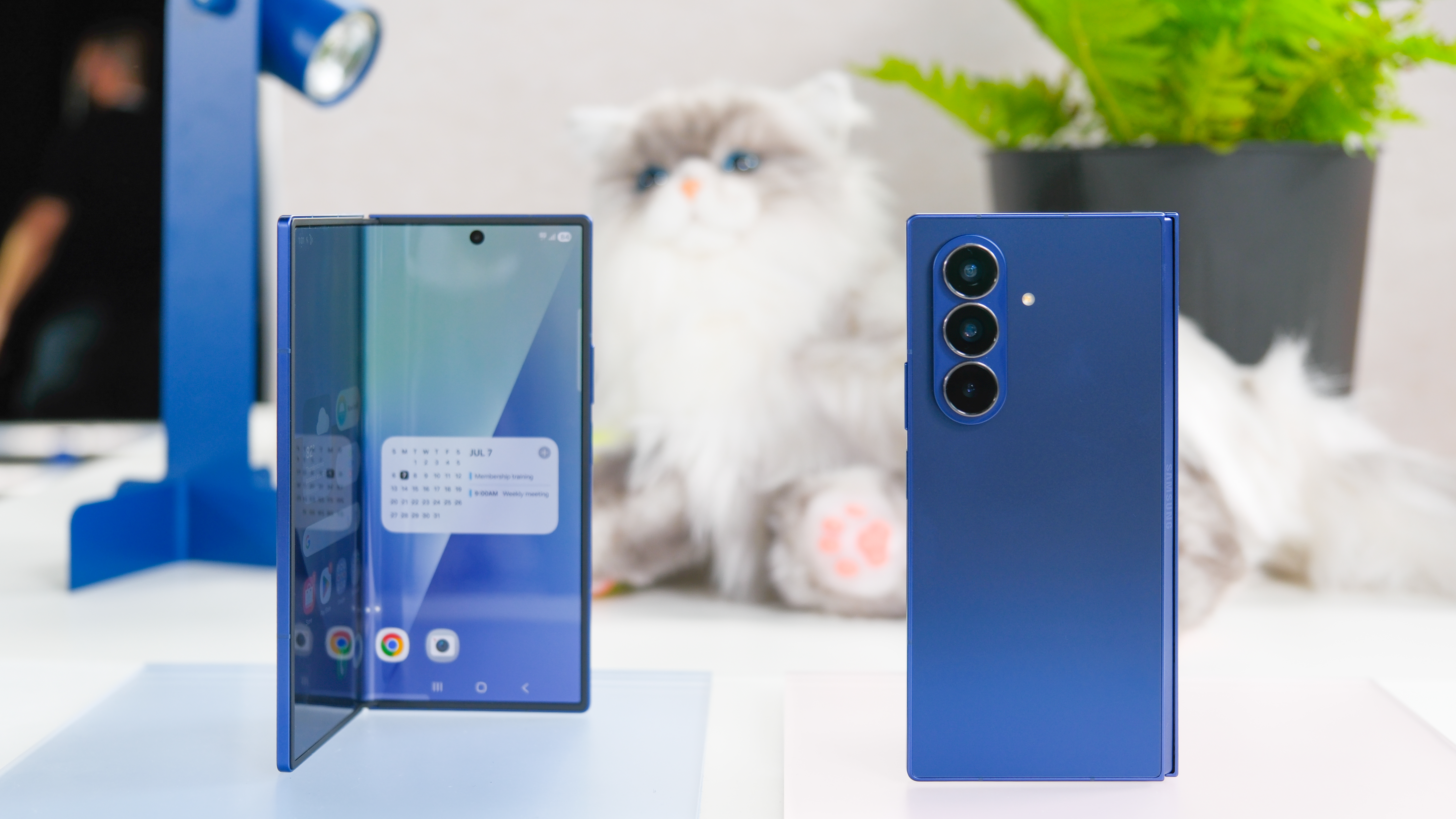 Two blue Samsung Galaxy Z Fold 7 devices with a stuffed cat behind them
