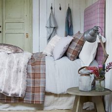 bedroom with white wall cloth hanger on wall and bed with white and checkered cushions