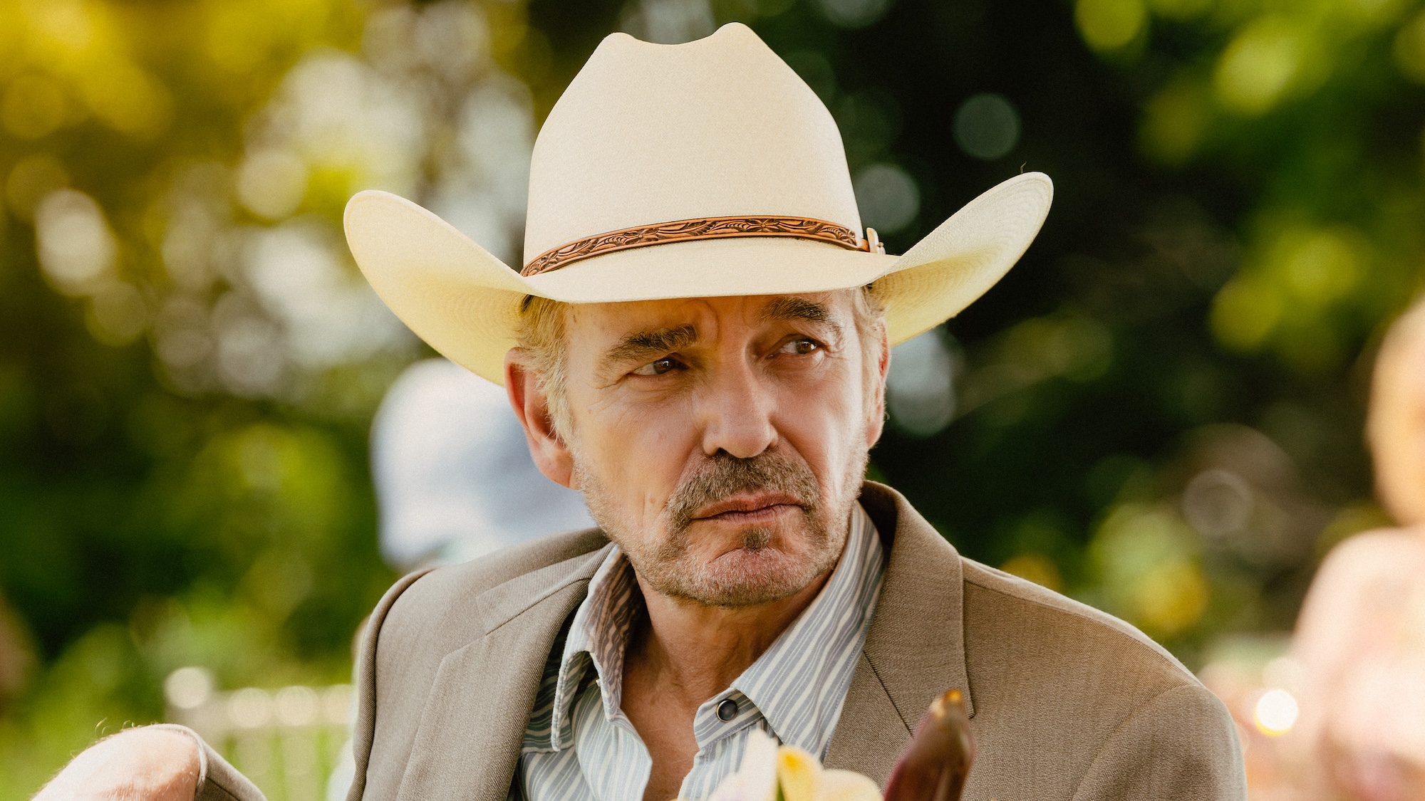 Tommy in cowboy hat sitting outside poolside in Landman Season 2