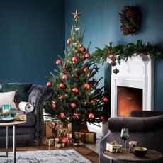 A decorated Christmas tree in a living room next to the fireplace