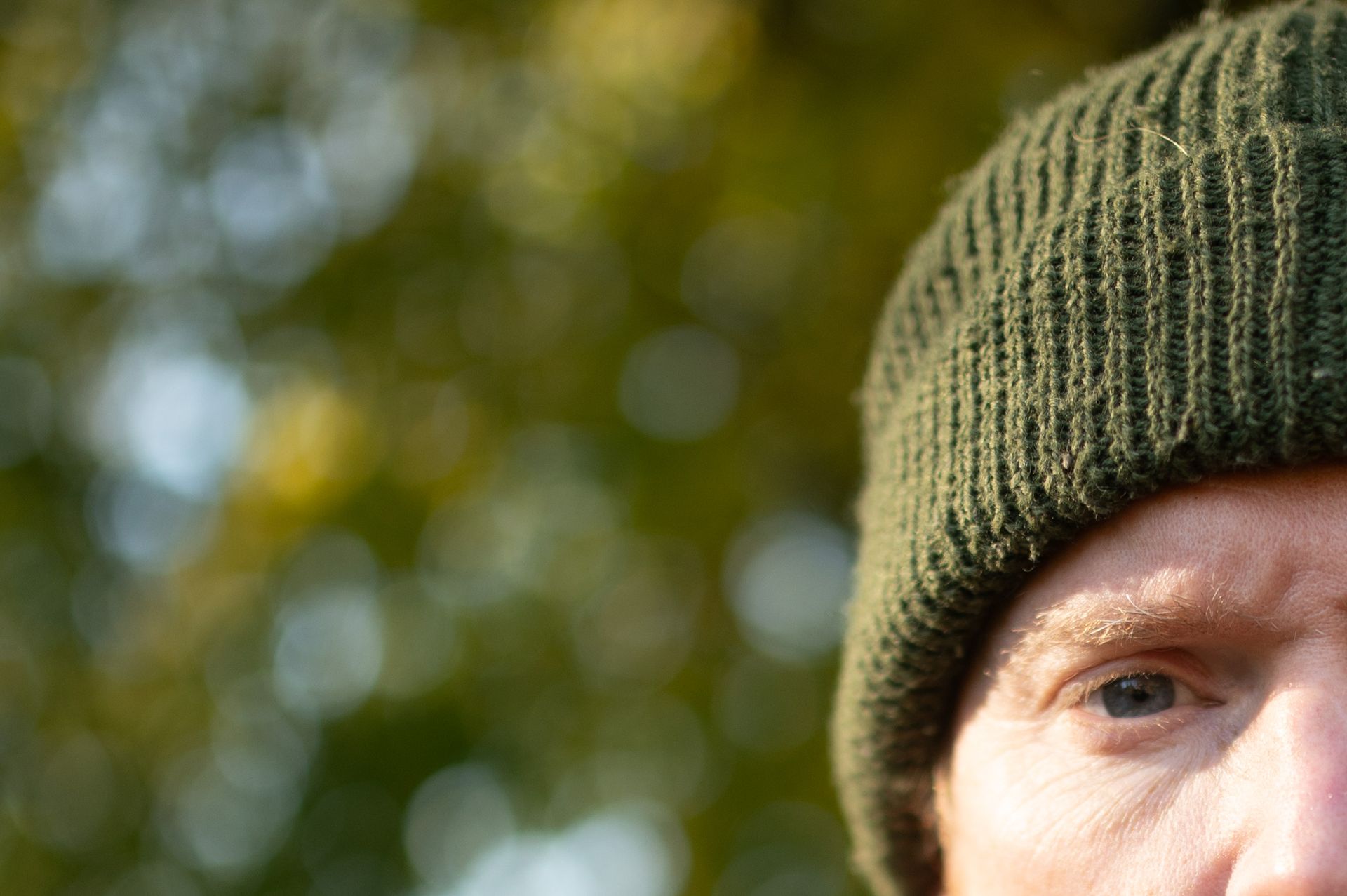 Portrait of a man in a shacket and beanie hat, outdoors with fall trees backdrop