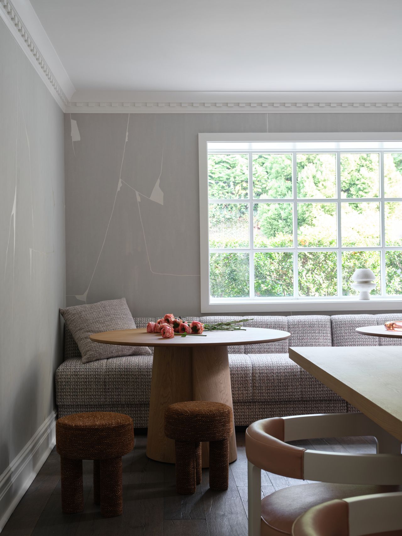 a corner of a room with grey walls, a round table, and two stools