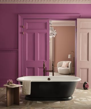 magenta bathroom with black roll top tub, pale pink view inside bedroom with matching door, side table, parquet floor