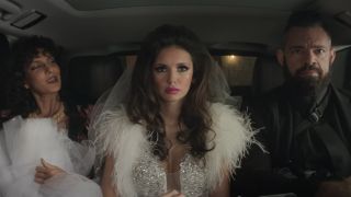 Nina Dobrev sits in-between her captors in a gawdy wedding get up in The Out-Laws.