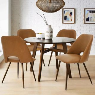 A small round dining table, four leather dining chairs, and textured pendant lights