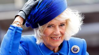 Camilla, Queen Consort holds onto her hat in the wind as she attends the 2023 Commonwealth Day Service