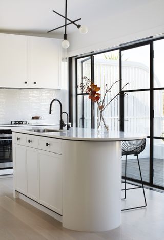 An organized kitchen with white cabinets and drawers under the sink