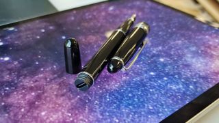 A photo of the Adonit Star stylus with the cap to the side on a screen that has a galaxy background