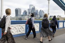People walk over the Thames with the City of London in the background before the UK general election (Photographer: Jason Alden/Bloomberg via Getty Images)