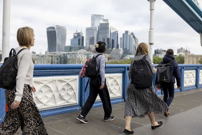 People walk over the Thames with the City of London in the background before the UK general election (Photographer: Jason Alden/Bloomberg via Getty Images)