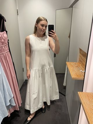 Woman in dressing room wearing white dress and black ballet flats