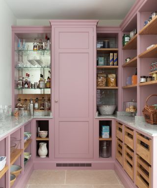 Walk-in pantry ideas with pink cabinetry and bar area with marble-backed open shelving