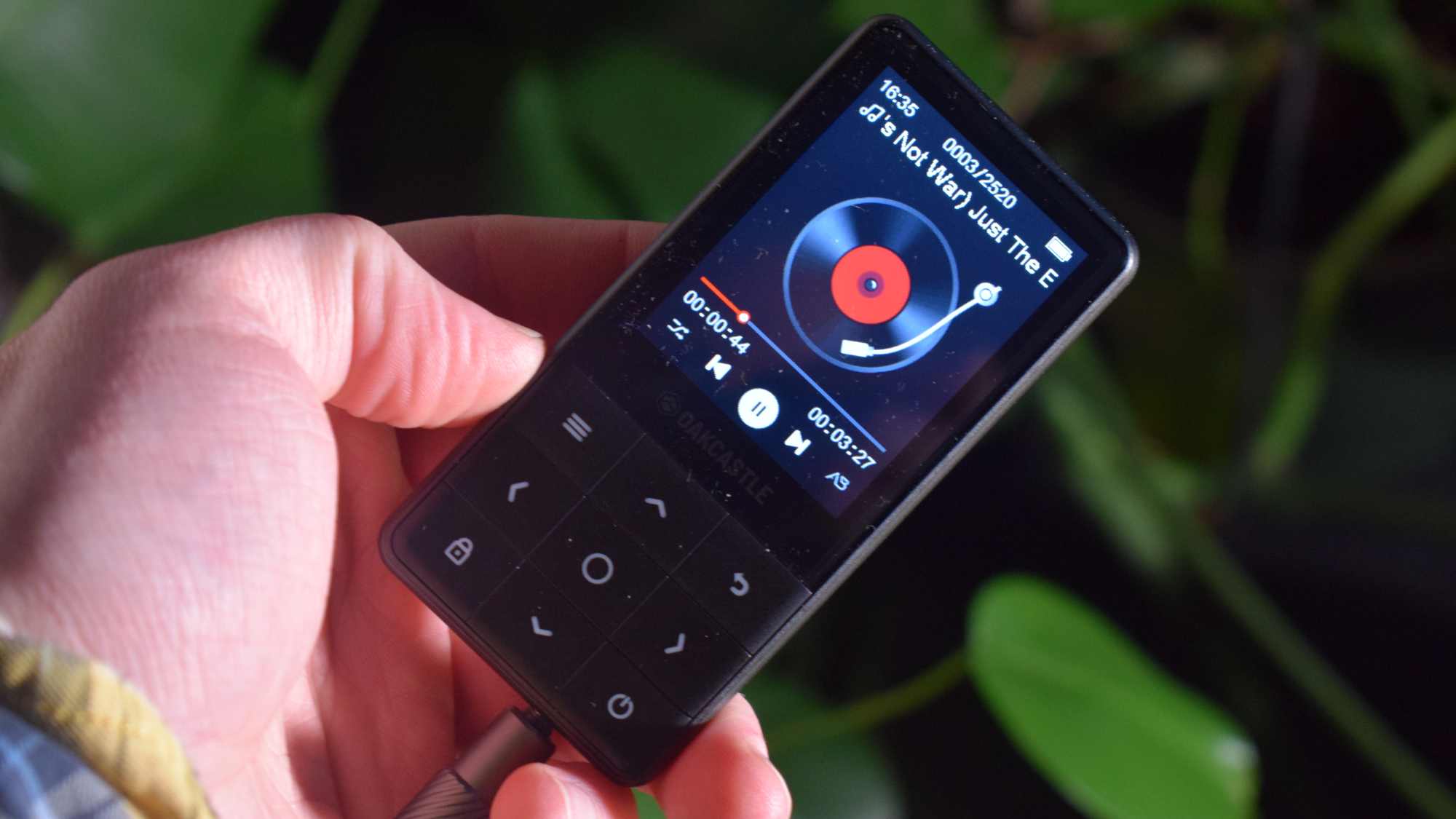 The Oakcastle MP300 in a hand, showing music playback.