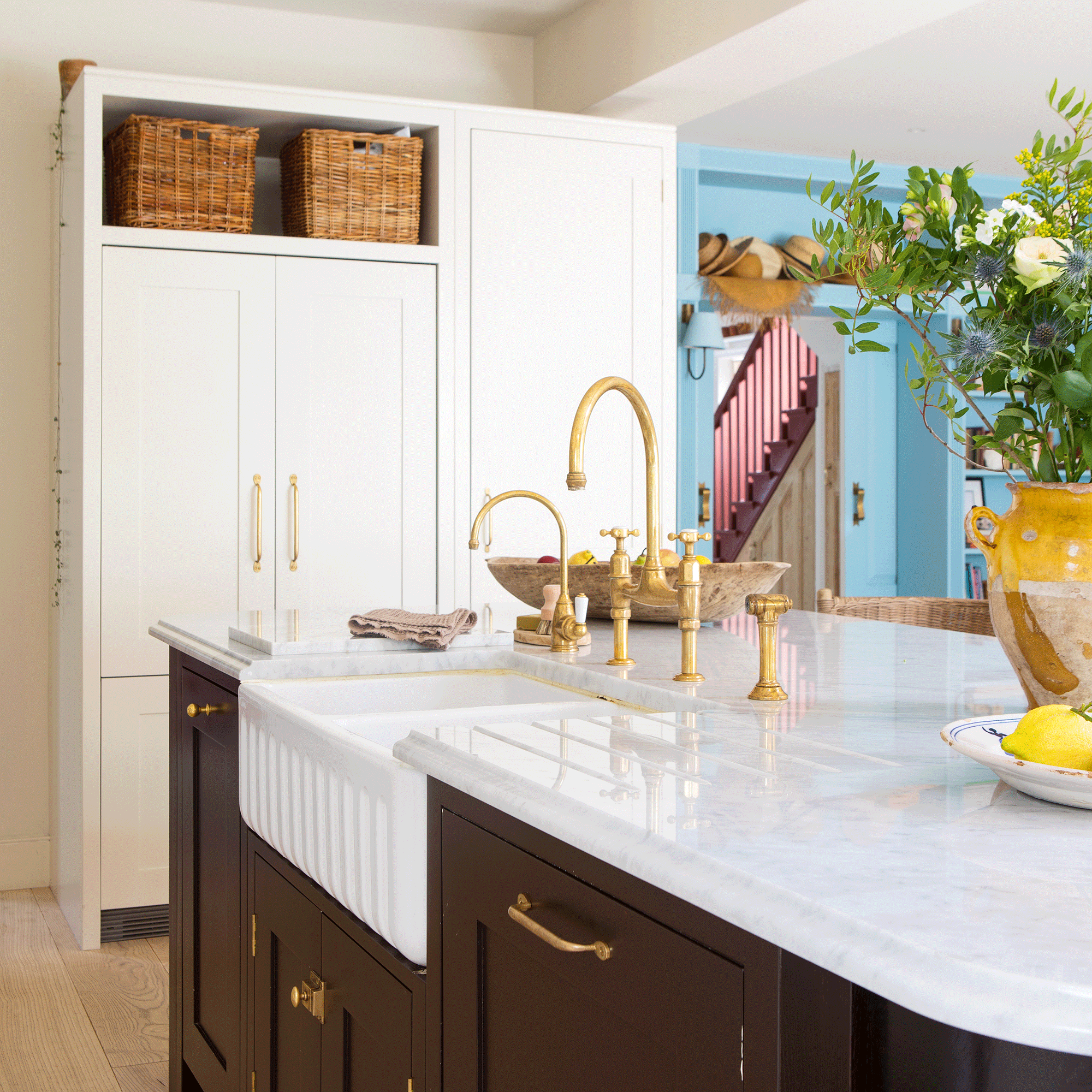 a large neutral kitchen with a kitchen island and Belfast sink and a blue walls with sliding door and bookcase