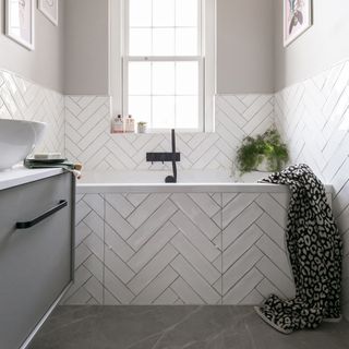 white and grey bathroom with chevron tiles on wall and bath