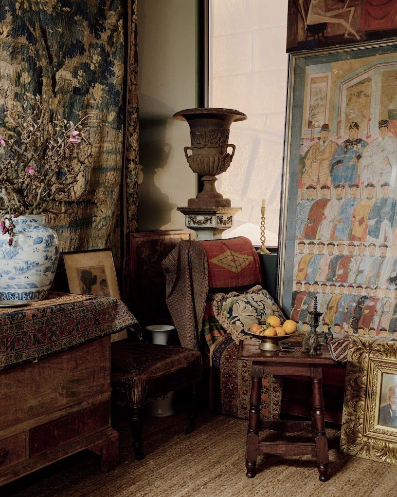 A series of ancient artifacts including amphoras, intricate tapestries, wooden furniture, and china porcelain decorate a softly lit room.