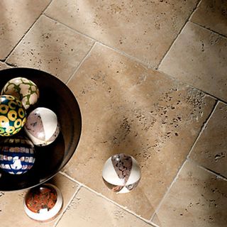 Sicilian White Tumbled Travertine Opus Floor Tiles in brown with a black bowl and glass globe decorations