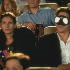 Julia Roberts and Hugh Grant sit in a movie theater in the movie Notting Hill, and Grant wears swimming goggles