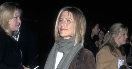 Jennifer Aniston wearing a suede coat, blue jeans, and snakeskin boots