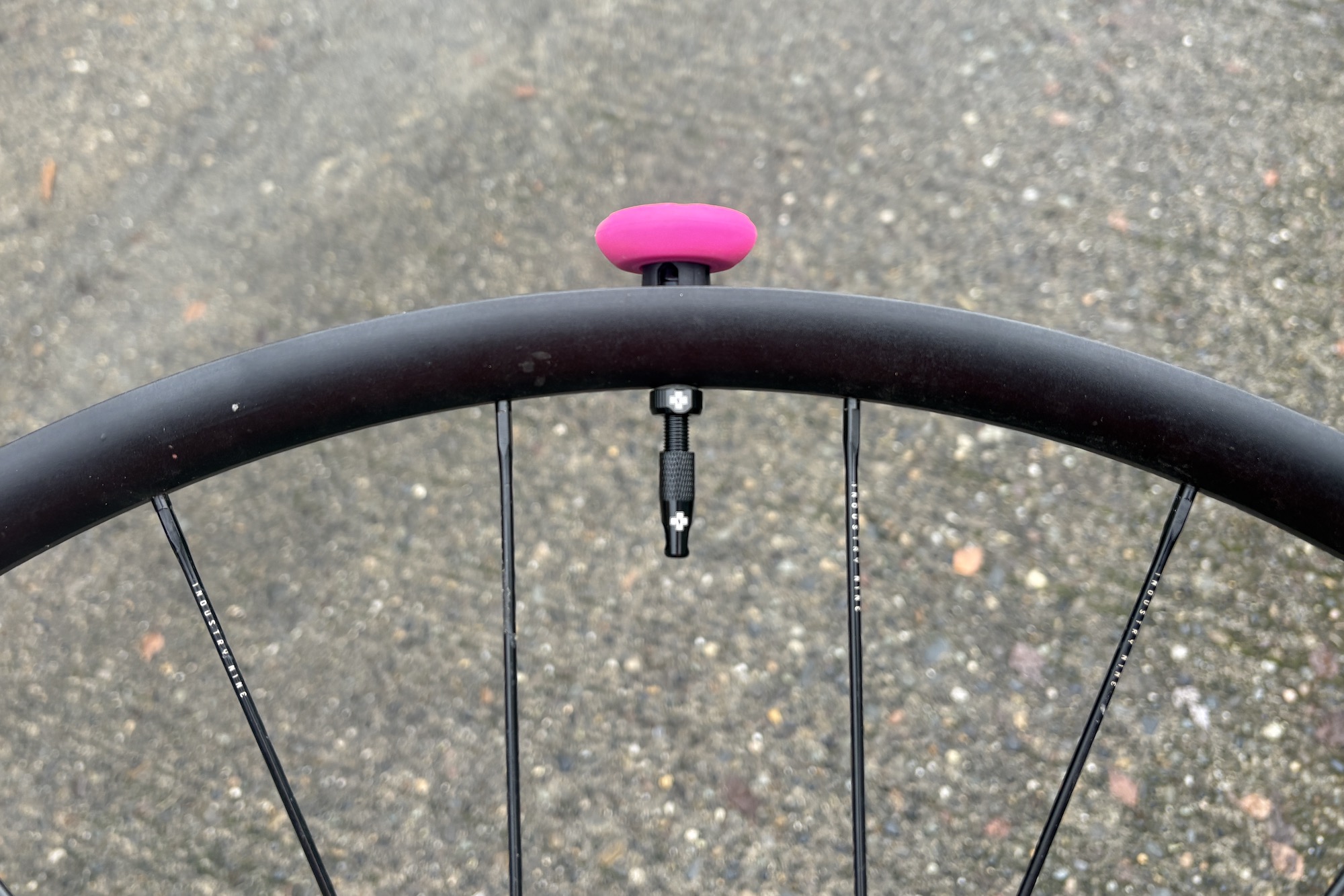 The Muc-Off Stealth AirTag holder mounted to a value which has been inserted into a bike rim without a tyre to show how it works.