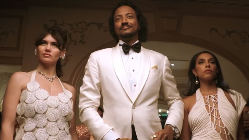 Koumba dressed in white tux with beautiful women by his side in Pluribus Episode 6