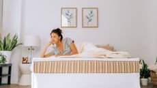 A woman lying on the Essentia Classic REM5 Mattress against a white wall.