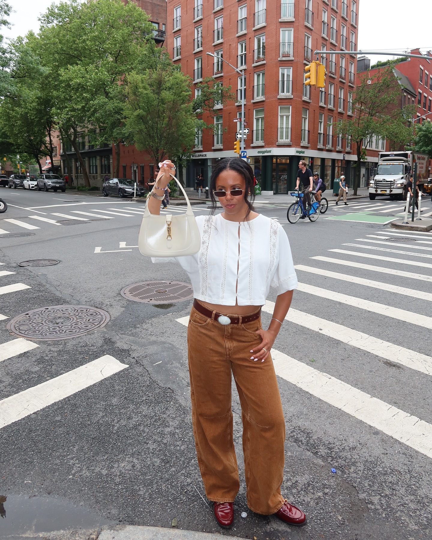 Fashion editor Sierra Mayhew wears a brown cord trousers a brown belt a white broderie top and carriers a white Gucci jackie.