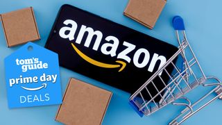 Smartphone with Amazon logo shown in mini shopping cart with three boxes