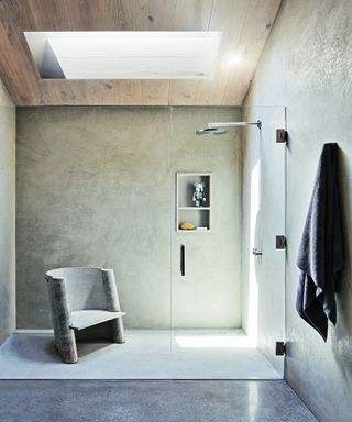 minimalist neutral shower room with concrete chair, wooden ceiling and skylight