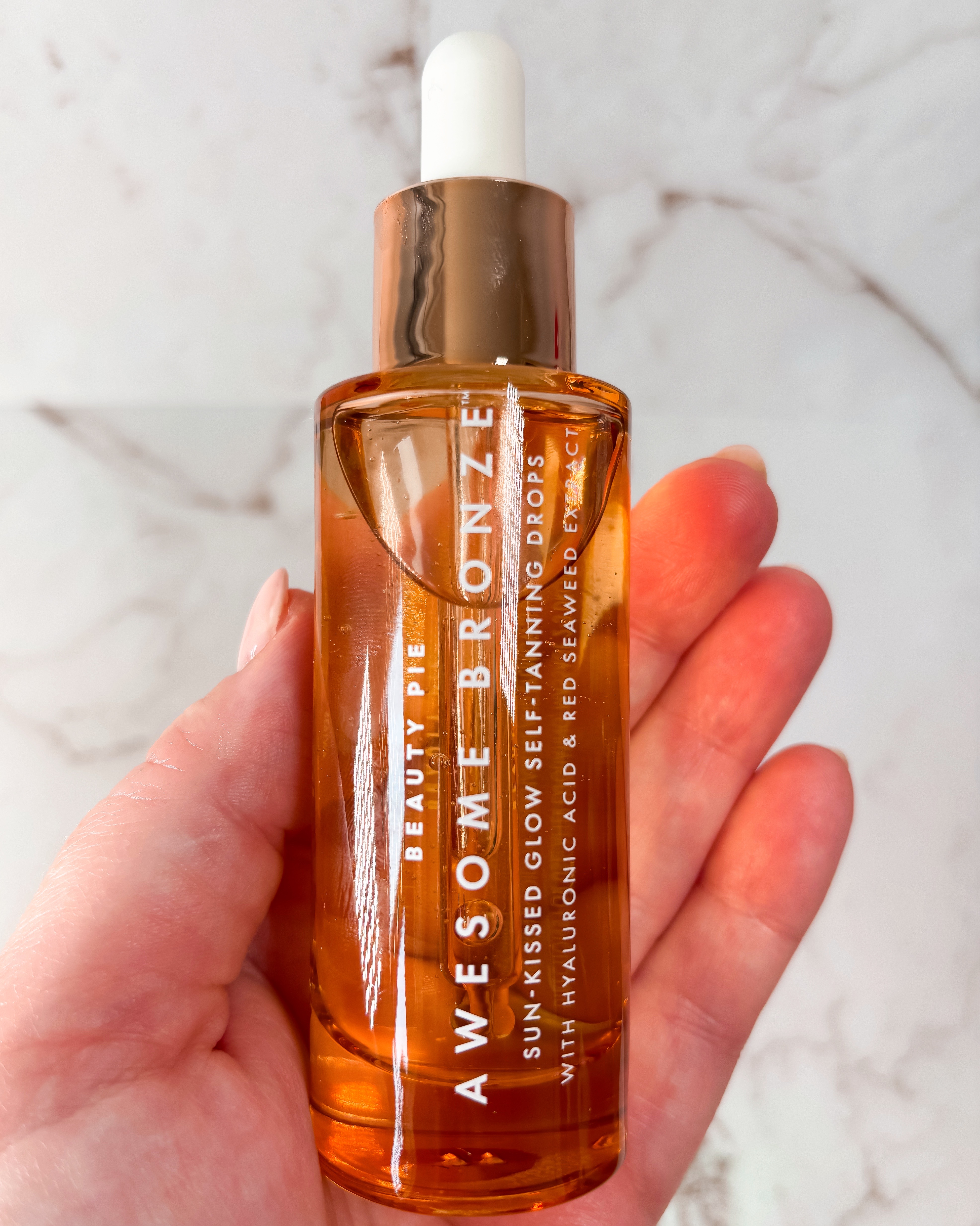 A photograph of the amber bottle that houses Beauty Pie's Tanning Drops
