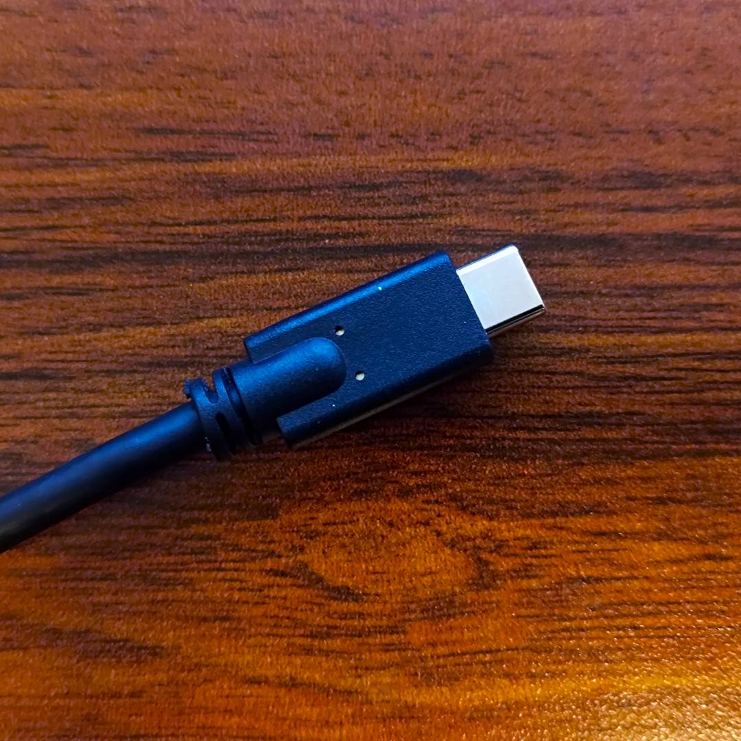 USB-C cable end on woodgrain desk.